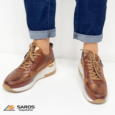 Ténis castanhos metalizados femininos com atacadores e sola branca usados com jeans