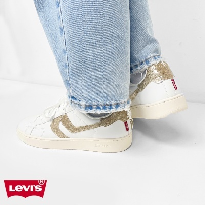 Ténis Levis brancos com detalhes dourados e jeans azuis claros