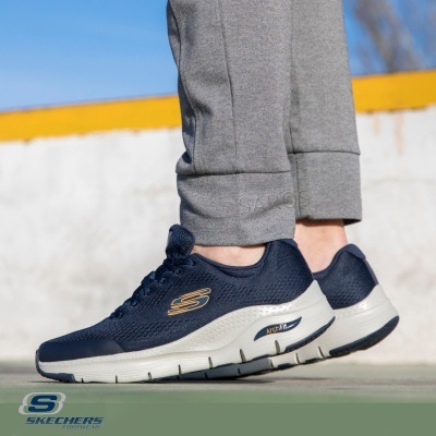 Ténis Skechers azuis escuros com sola branca usados com calças cinzentas