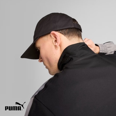 Homem de perfil com boné e blusão preto com detalhes cinzentos