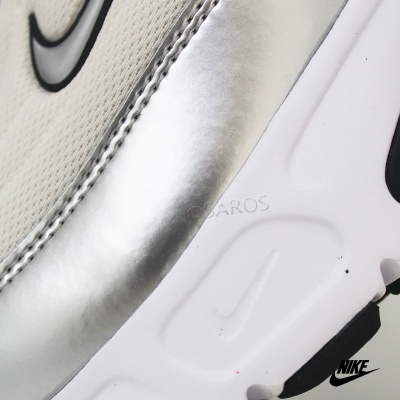 Close-up de ténis branco e prata com logótipos Nike em preto.