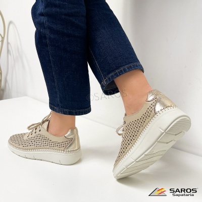 Sapatos baixos dourados perfurados com sola branca e jeans escuros