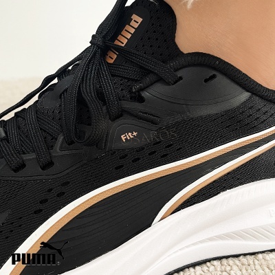 Ténis desportivos pretos PUMA com detalhes em bege e branco.