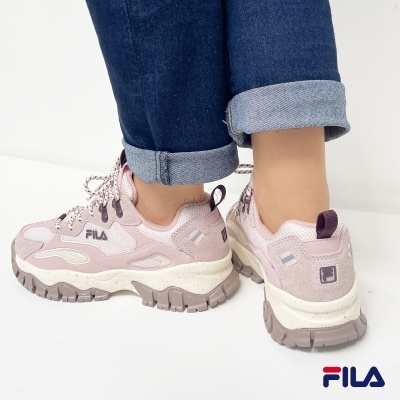 Tênis rosa claro e bege da FILA com sola robusta usados com calças de ganga azul.