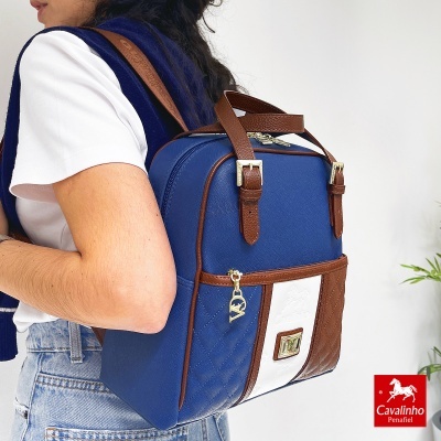 Mochila Cavalinho azul e castanha com detalhes em branco usada por pessoa