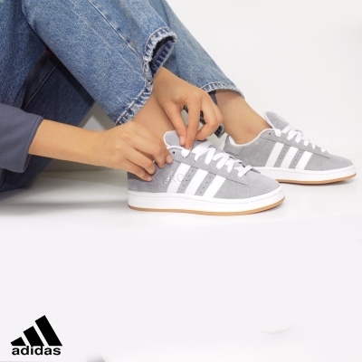 Ténis Adidas cinzentos com riscas brancas em fundo branco