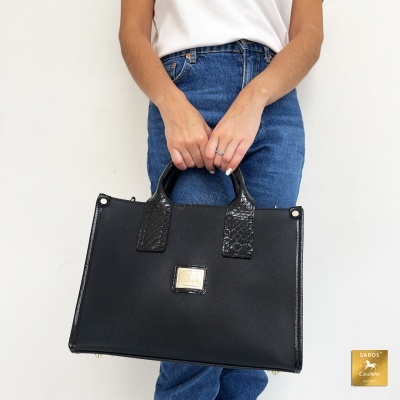 Mala de mão preta com texturas lisas e padrão croco nas alças e moldura.