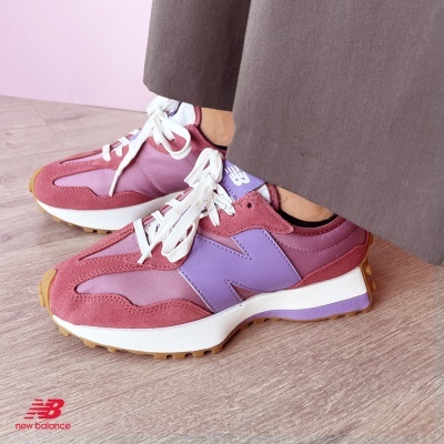 Sapatilhas New Balance rosa e lilás com cadarços brancos usadas com calças castanhas.