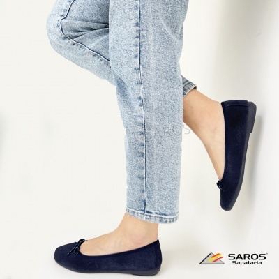 Sapatilhas femininas azuis escuras com laço decorativo e calças de ganga