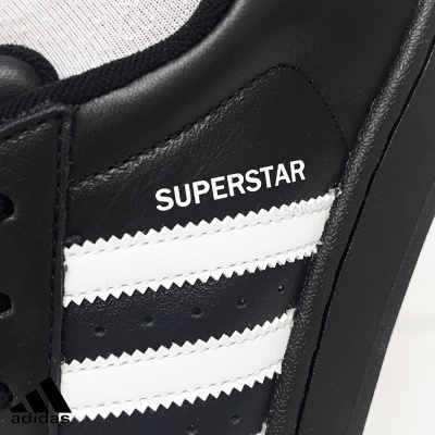 Sapatilha preta e branca adidas modelo SUPERSTAR em couro sintético.