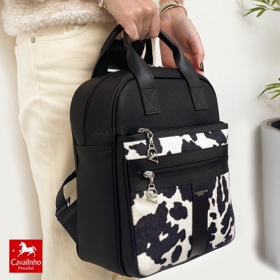 Mochila preta e branca com padrão animal print e detalhes em preto, fechos metálicos e etiqueta com texto Cavalinho Club Del 1975.