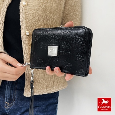Carteira preta Cavalinho com padrão em relevo e fecho metálico, segurada por pessoa