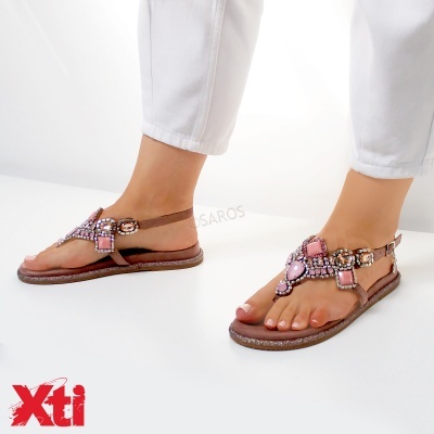 Sandálias rasas femininas castanhas com pedras rosas e castanhas, usadas com calças brancas.