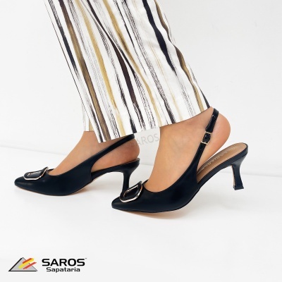 Sapatos de tacão médio pretos com fivela metálica e calças de riscas verticais castanhas, pretas e douradas