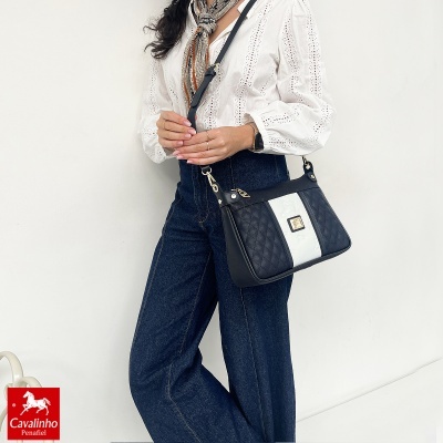 Mala de ombro em couro preto e branco com padrão acolchoado e placa dourada ao centro