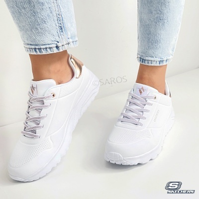 Sapatilhas Skechers brancas com atacadores cinza e detalhes bege usadas com jeans claros.