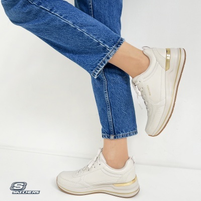 Ténis brancos Skechers com detalhes dourados usados com jeans azuis