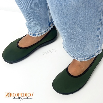 Sapatilhas verdes Arcopedico com sola preta e detalhe em preto, usadas com calças de ganga claras.