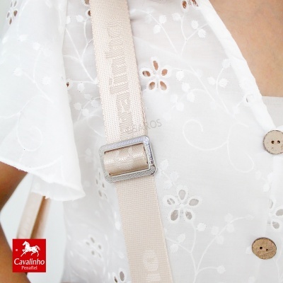 Peça de vestuário branca com bordados florais e botões de madeira, fita bege com fivela metálica