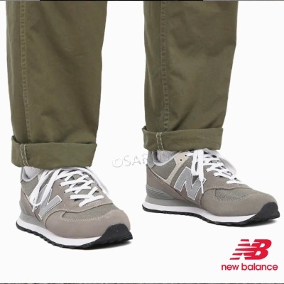 Ténis New Balance cinzento claro e branco usados com calças castanhas