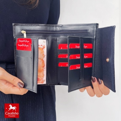 Carteira preta de couro aberta com vários cartões vermelhos nas mãos de uma pessoa.