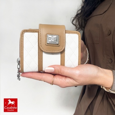 Carteira Cavalinho bege e branca com textura matelassê, segurada na mão.
