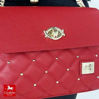 Mala vermelha de pele matelassê com detalhes dourados e fecho em forma de olho