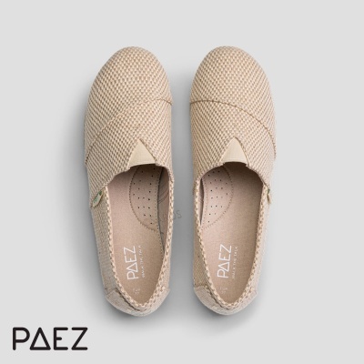 Sapatos tipo alpargatas bege claro com textura tecida e sola clara sobre fundo cinzento