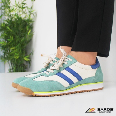 Tênis desportivo verde água, azul e branco, com atacadores brancos e sola castanha, usados com calças pretas