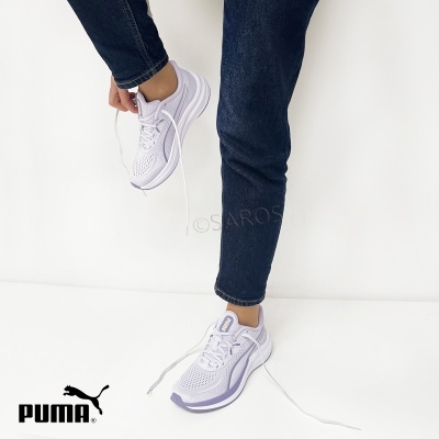 Ténis Puma brancos com detalhes lilás usados com calças de ganga azul escuro