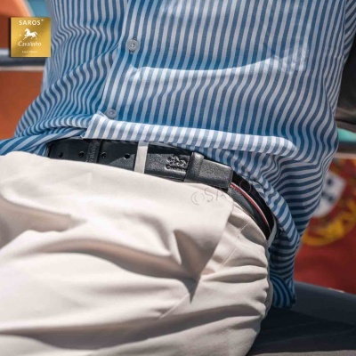 Pessoa vestindo camisa às riscas azuis e brancas com calças bege e cinto preto de pele com emblema de cavalo.