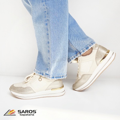 Ténis bege e dourado com sola branca usados com jeans azuis claros