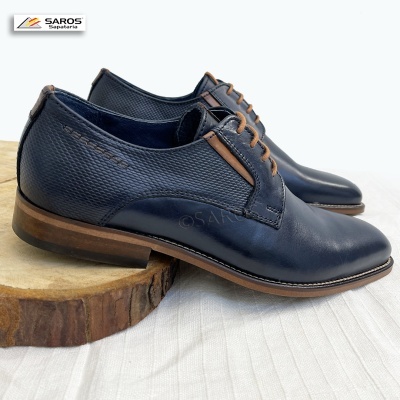 Sapatos de couro azul escuro com atacadores castanhos e sola castanha sobre madeira