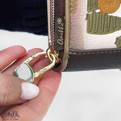 Bolsa com fecho dourado e etiqueta Anekke junto a mão feminina