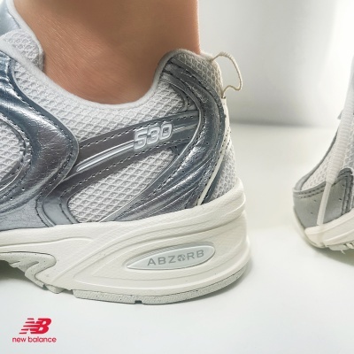 Sapatilha desportiva New Balance branca com detalhes prateados e cinzentos e texto ABZORB