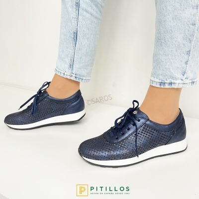 Sapatilhas femininas azul escuro perfuradas com atacadores e sola branca usadas com jeans azuis