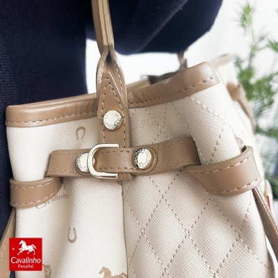 Mala bege com padrão em losango, alças e detalhes em pele castanha com fivelas douradas gravadas.