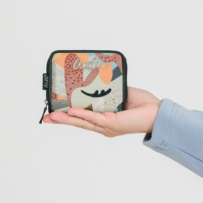 Carteira pequena colorida com padrão abstrato e pedras vermelhas, sendo segurada por uma mão.