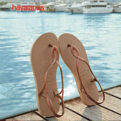 Chinelos Havaianas rosa claro com tiras finas em cais de madeira junto ao mar