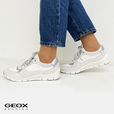 Tênis desportivo branco e cinza com solado branco e calças de ganga azul