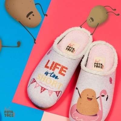 Chinelos rosa claro com estampas de batata e texto divertido, sobre fundo azul e rosa.