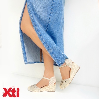 Sapatos de cunha bege com padrão perfurado e saia azul de ganga