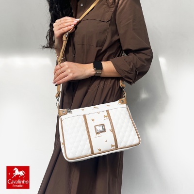 Mala de senhora Cavalinho branca com padrão castanho ao ombro de mulher em vestido castanho