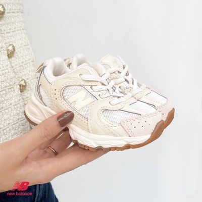 Tênis infantil New Balance bege e branco com sola castanha sendo segurado na mão