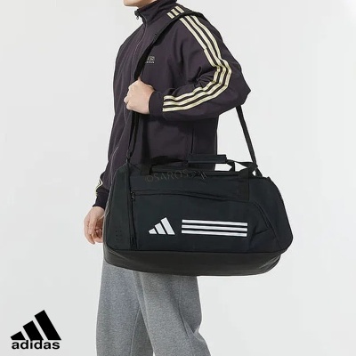 Saco desportivo Adidas preto com três riscas brancas carregado ao ombro