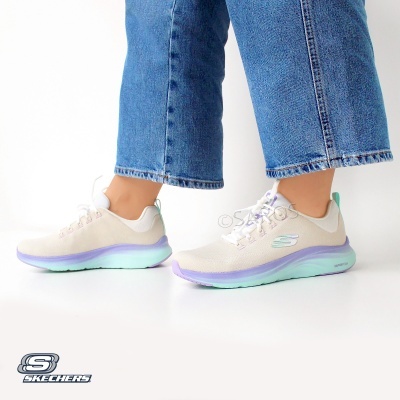 Ténis Skechers bege com detalhes lilás e sola verde clara usados com jeans azuis.