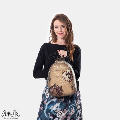 Mochila bege com padrão floral castanho e branco, segurada por mulher