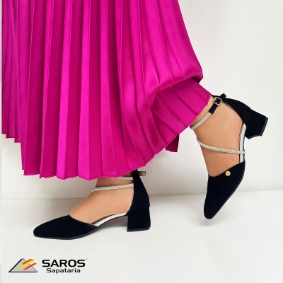 Sapatos pretos com tiras prateadas junto a saia rosa plissada