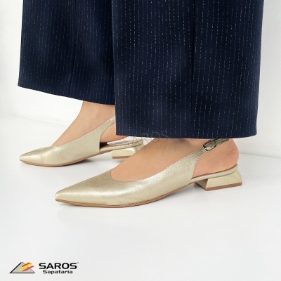 Sapatos dourados de salto baixo com alça, usados com calças azuis às riscas num fundo branco.