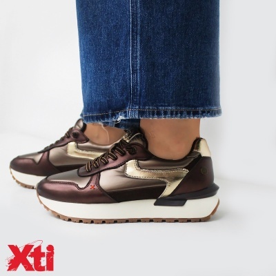 Ténis XTI castanho e dourado com sola cremosa e calças de ganga azul